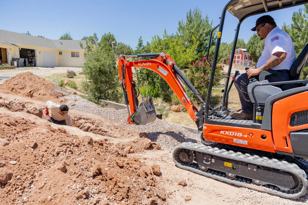 Mini excavator digging a water line trench in St. George, UT